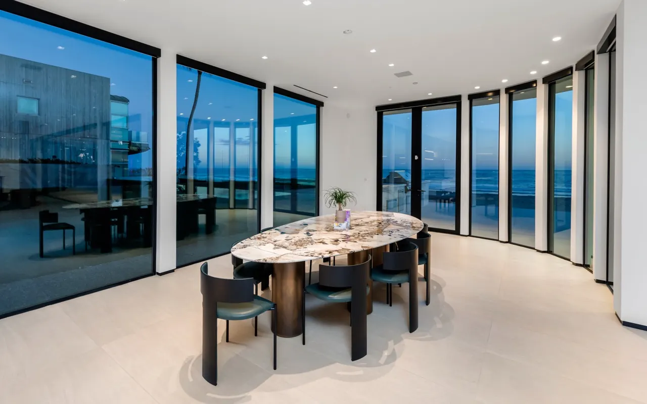 A dining room inside a curved wall of glass looking onto the ocean