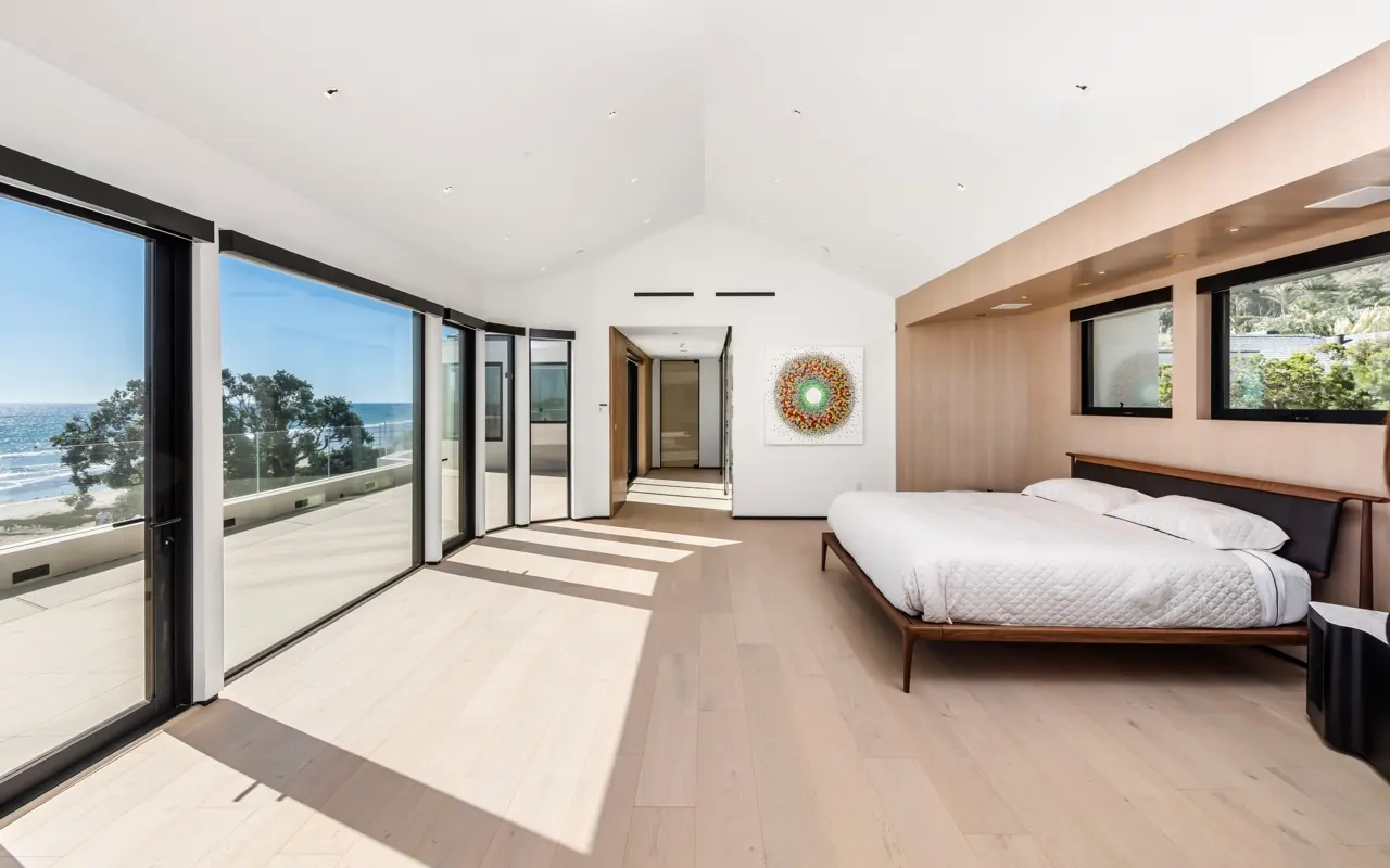 A bedroom with a timber-lined wall and floor-to-ceiling glass onto the terrace and ocean