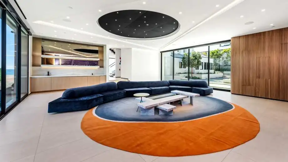 A large open living room with a circular sunken lounge and full glazing to the pool