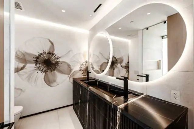 A powder room with a hand-painted floral mural, stone trough basin and backlit circular mirror
