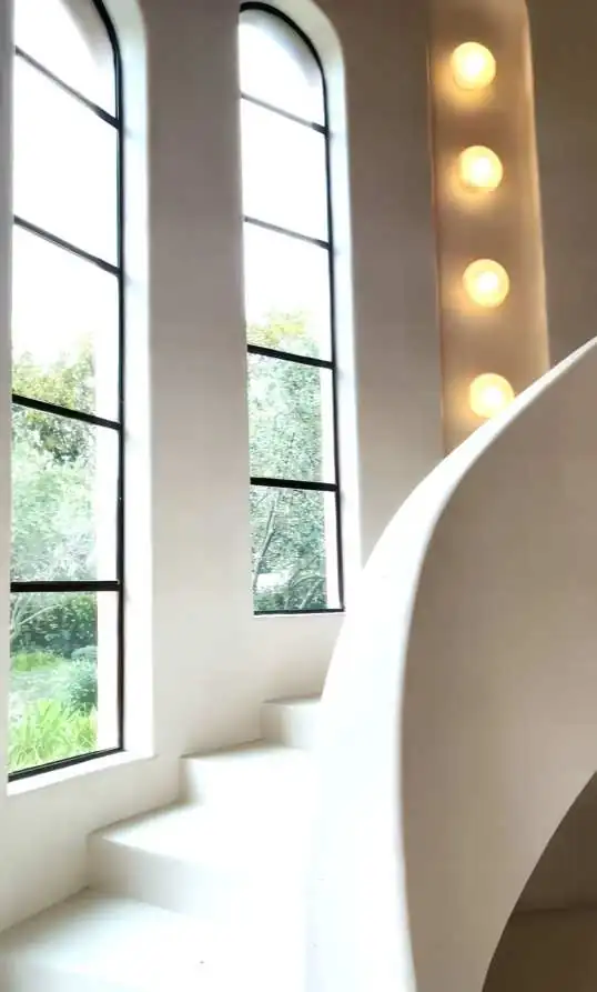A curved entry hall with arched windows and a sculptural stair