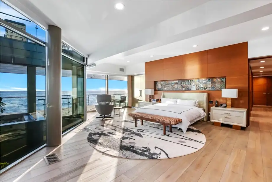 A bedroom with full-height glazing onto the ocean and a low bed