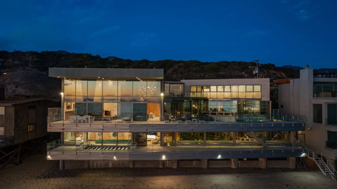The ocean elevation at night, three lit floors of glass above the sand