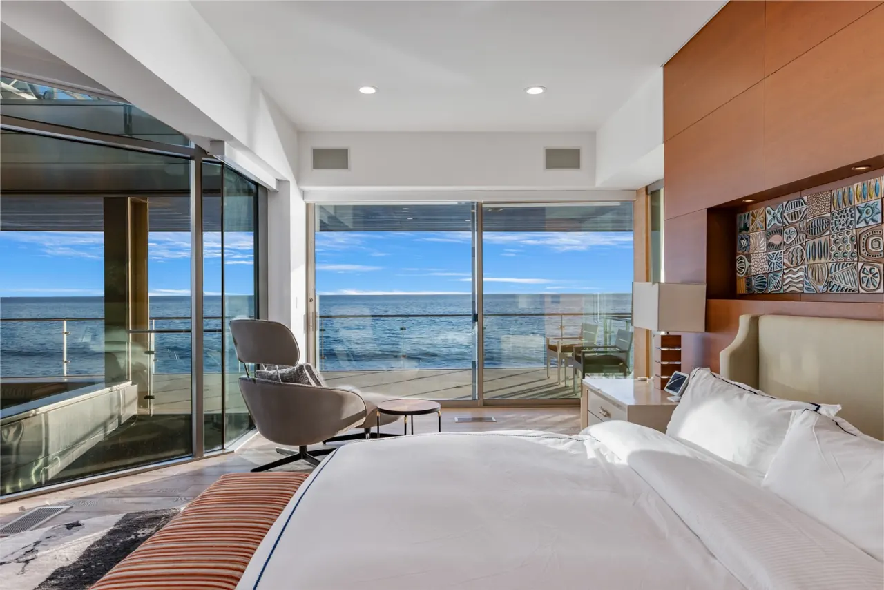 The primary bedroom looking through two walls of glass onto the ocean