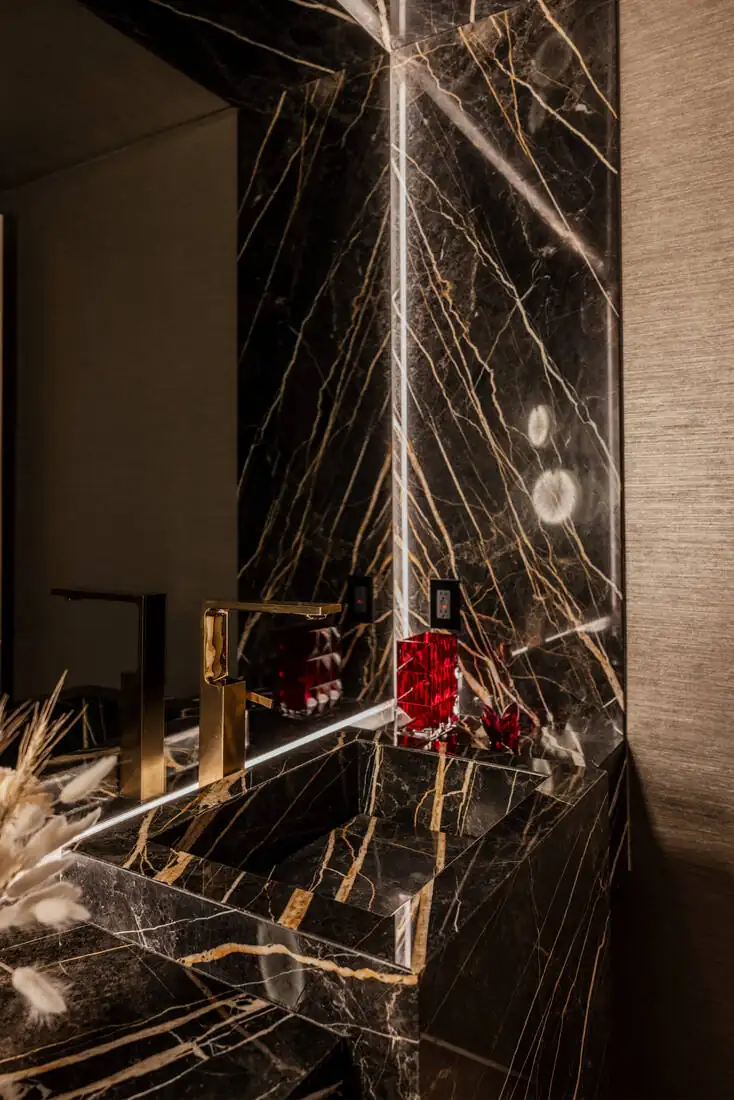 A close view of a black-and-gold marble bar front with brass shelving and glassware