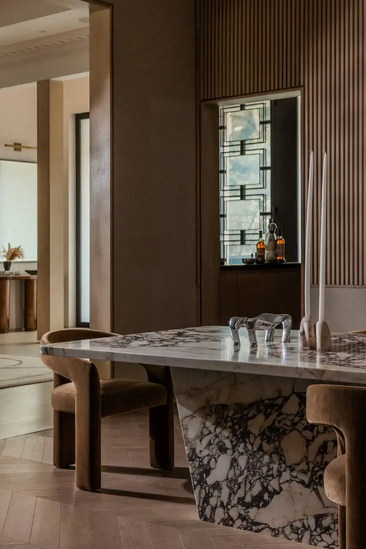 A bar area with a figured stone counter, low lighting and glassware on the top