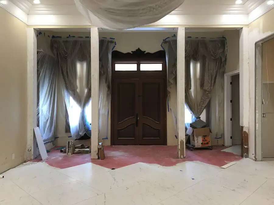 The entry before work: an arched timber front door flanked by draped plaster columns