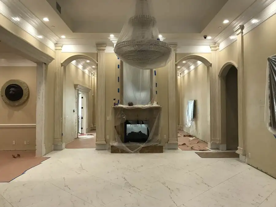 The main reception room before work: plaster columns, arched openings, a crystal chandelier under protective sheeting