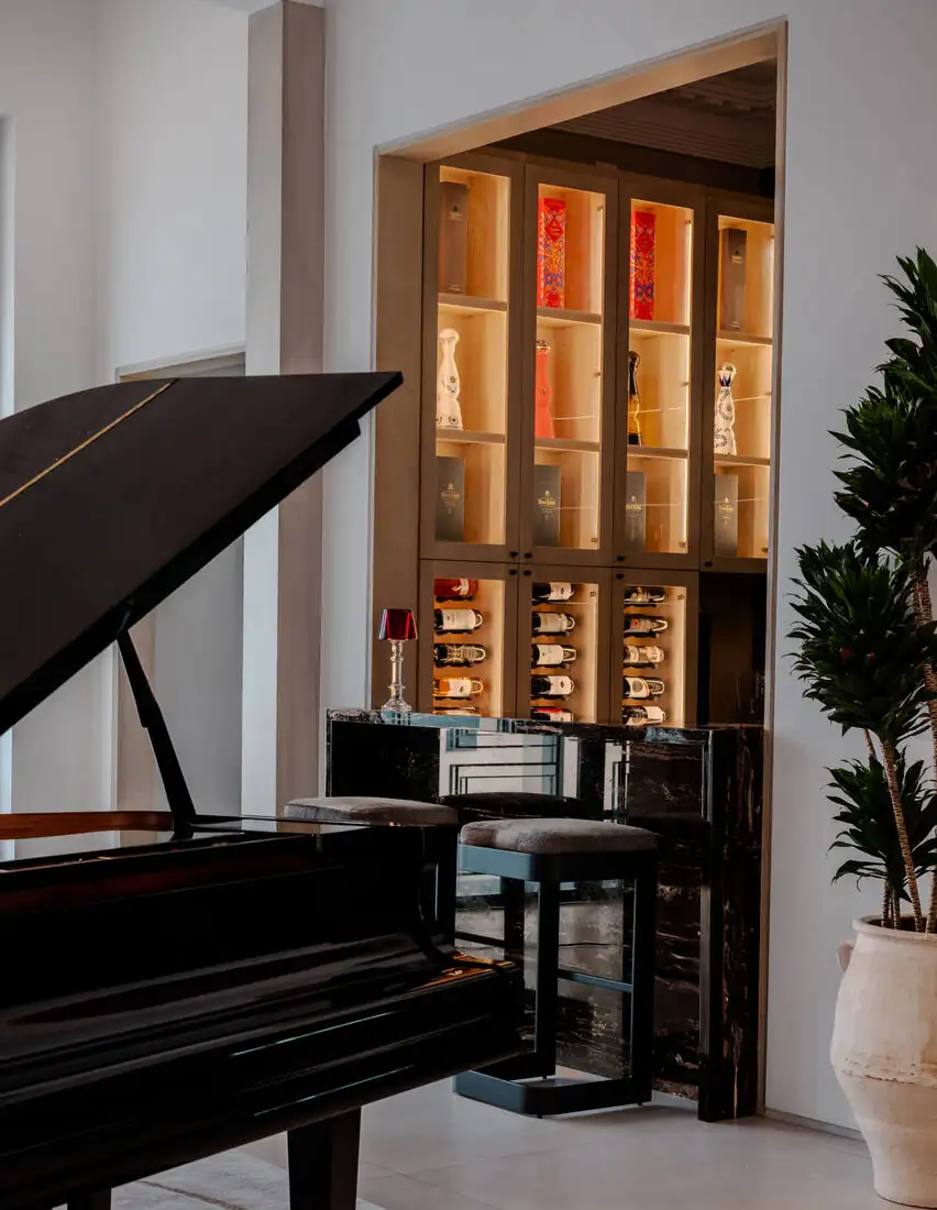 A backlit amber display cabinet beside a grand piano