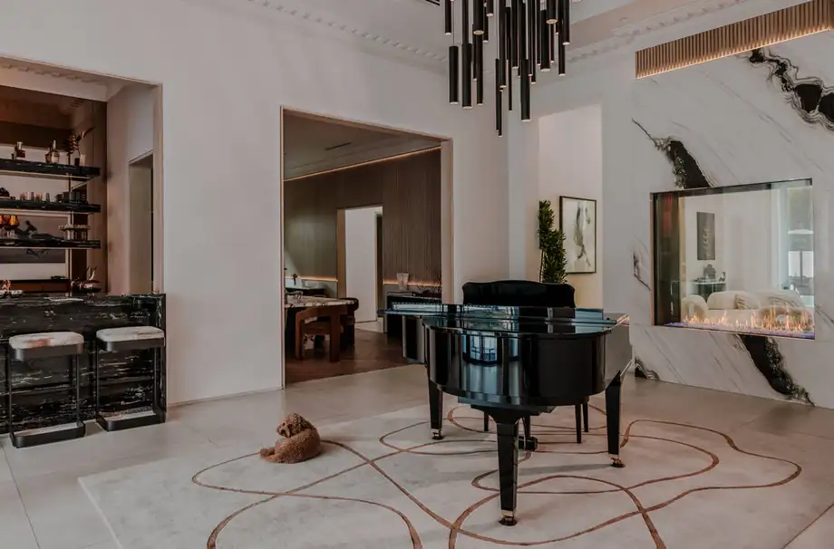 A tall reception room with squared openings, a linear black chandelier and a marble slab wall