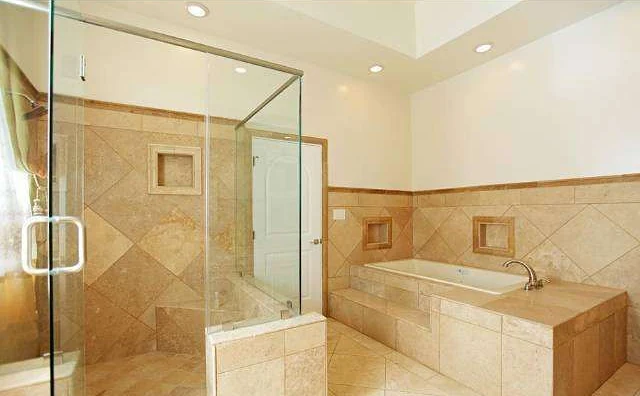 The primary bathroom before: glass shower and tiled tub surround