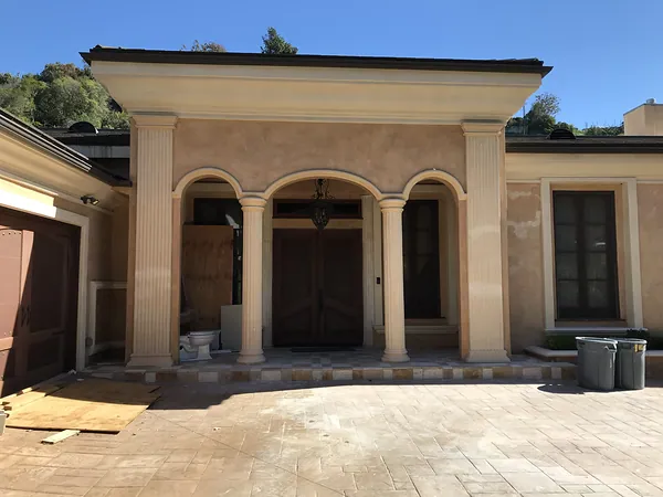 The front of the house before: arched loggia and stone pavers