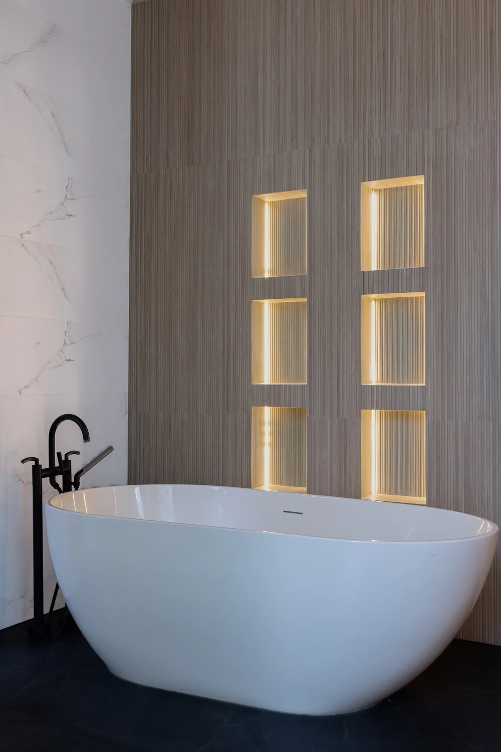 Kids’ bathroom with freestanding tub and lit stone niches