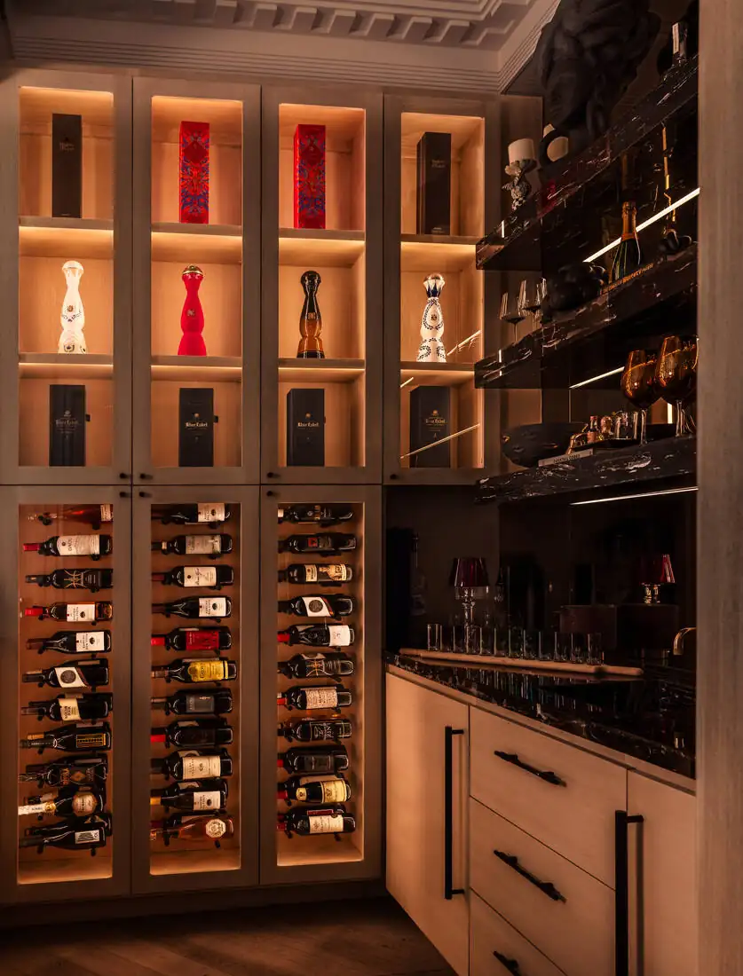 A wine room with backlit glass-fronted cabinets, timber racking and a service counter