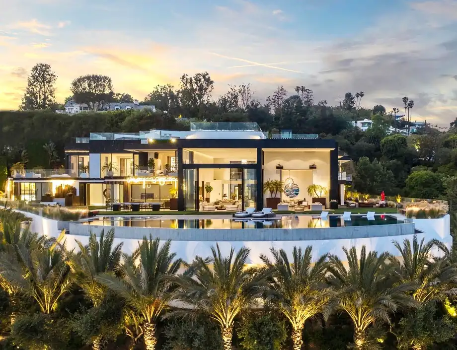 A hillside residence in Bel Air at dusk seen from the air, an infinity pool running along the ridge