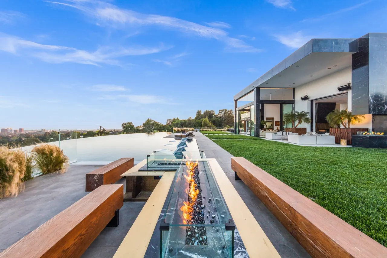 A long glass-sided fire feature between timber benches, running across the terrace toward the view