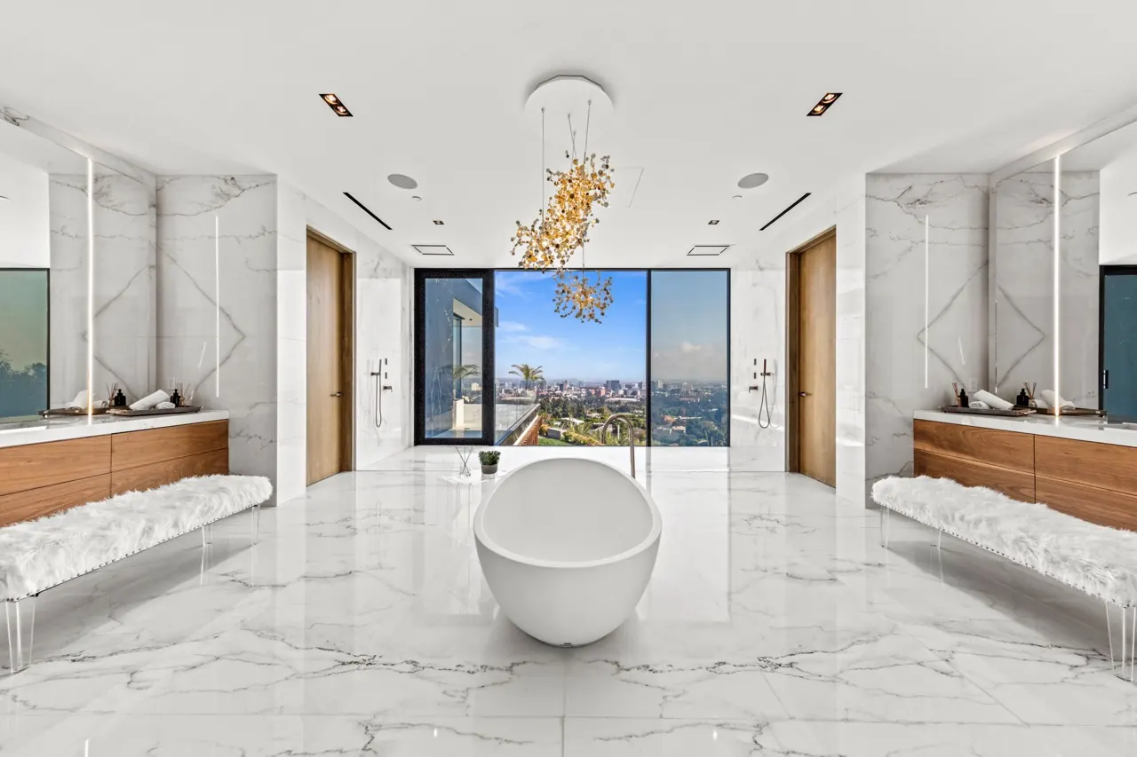 The primary bath: a freestanding tub centred on a window to the city, between marble-clad vanities