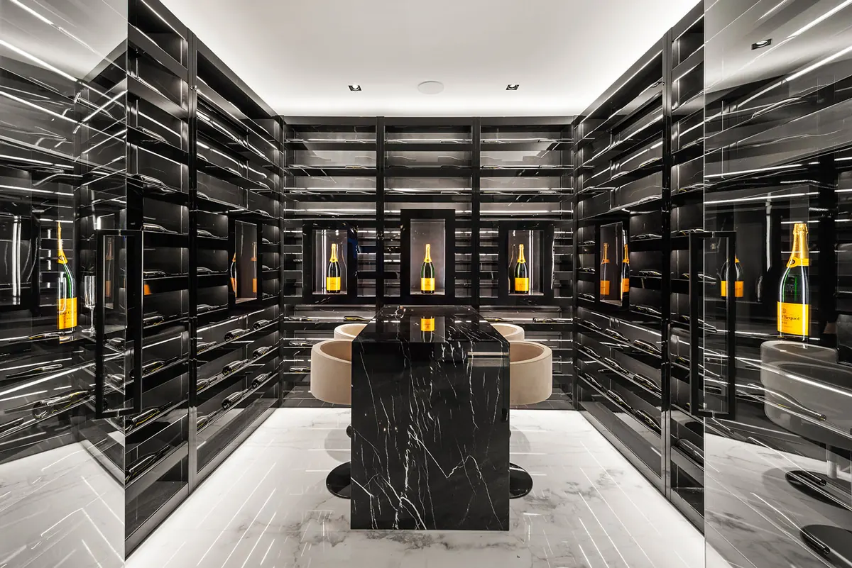 A wine room lined in black lacquered shelving around a black marble tasting table